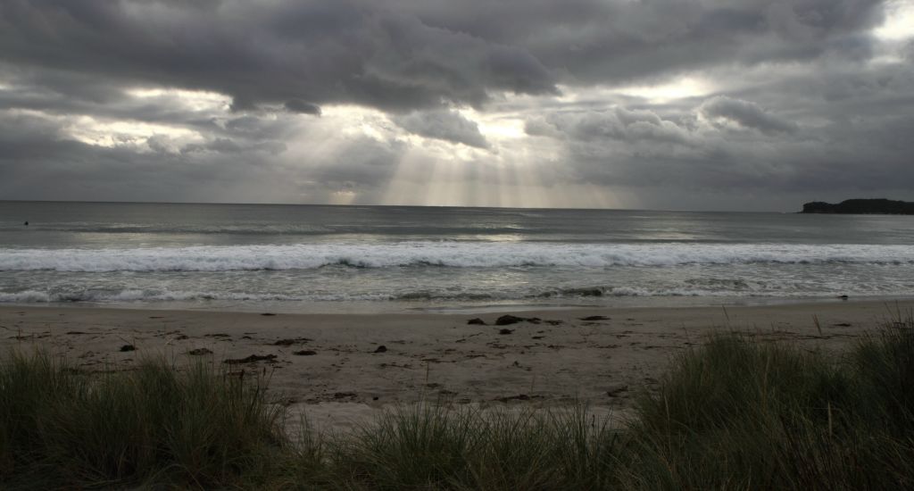 Morning sunlight streaming through a gap in the clouds Eaglehawk Neck Tasmania, Australia